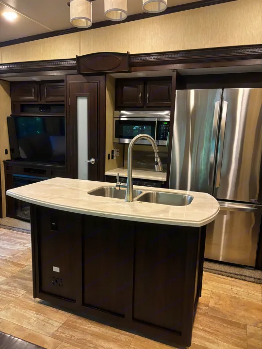 RV rental interior: spacious kitchen with dark wood cabinets, stainless appliances, island sink, & light flooring.. 4x4fcmp23h6007284 Columbus 2017