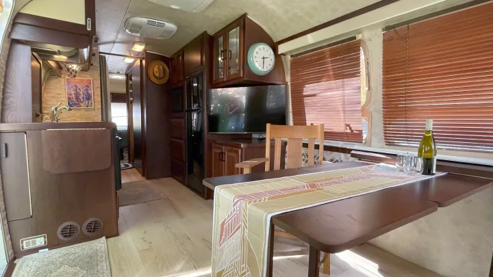 Step into this well-appointed RV rental! Features a full kitchen, dining area, TV, and ample wood cabinetry.. Airstream Excella 1990