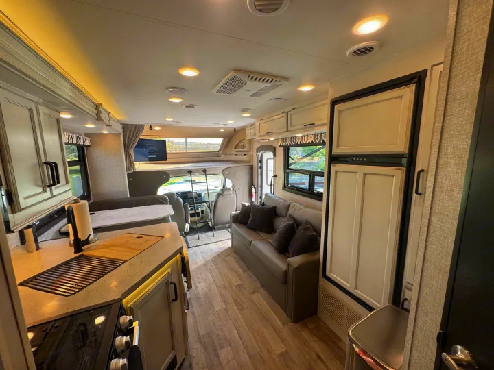 Inside this RV rental: a modern living space with kitchen, sofa, and cab-over bunk area. Ready for your adventure.. Entegra Coach Odyssey 2022