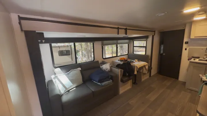 Experience a modern RV rental interior featuring a comfy couch, dining booth, kitchen area, and scenic windows.. Cruiser RV Shadow Cruiser 2024