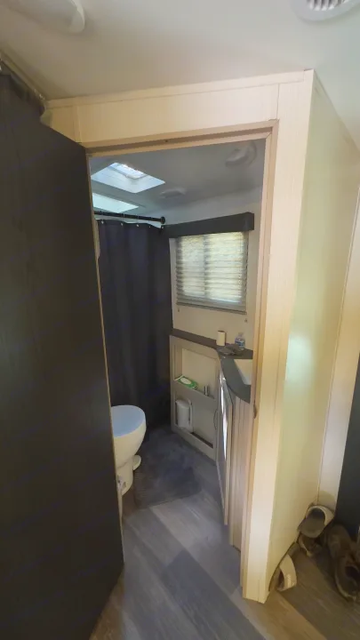Compact RV rental bathroom interior, featuring a toilet, shower curtain, vanity, and window for your travels.. Cruiser RV Shadow Cruiser 2024