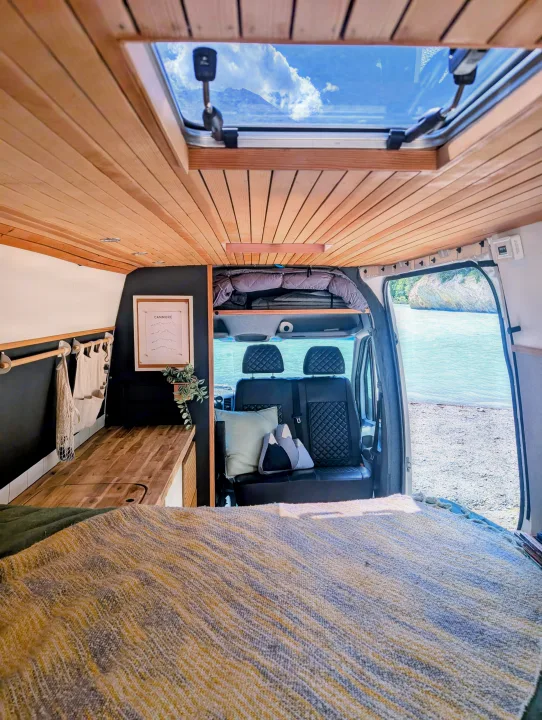Cozy RV rental interior with wooden ceiling, skylight, and scenic water view, perfect for van life adventures.. Mercedes-Benz Mercedes Sprinter 2500 2015