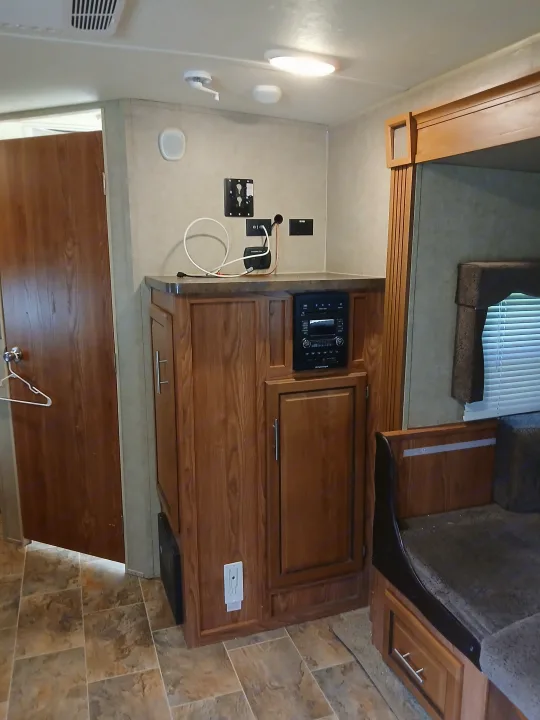 An RV rental's cozy interior, with rich wood cabinetry, entertainment setup, and dinette seating.. Forest River Rockwood Ultra Lite 2016