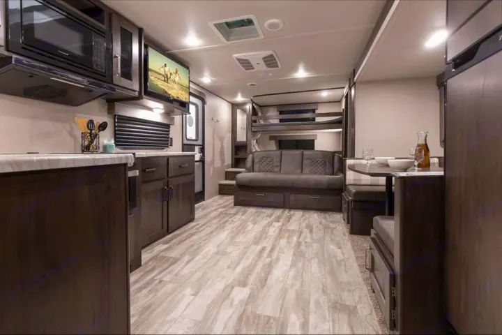 This RV rental's spacious interior features a full kitchen, living area with bunk beds, and a cozy dining space.. xpolar 265bh 2023