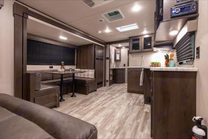 This rv rental features a bright, modern interior: a living area with a dinette, a full kitchen, and light wood flooring.. xpolar 265bh 2023