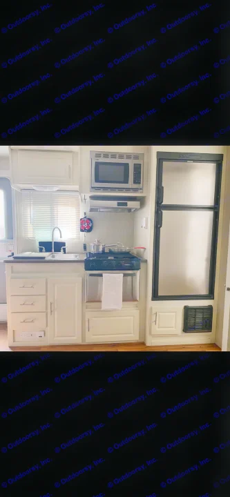 Clean RV rental kitchen showing microwave, refrigerator, stove, and sink with white cabinets and stainless steel appliances.. Cruiser RV Fun Finder X 2011