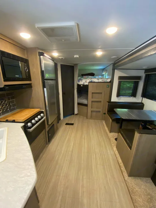 Step inside this RV rental, featuring a full kitchen with microwave, comfy dinette, and bunk beds. Light wood floors enhance the space.. Keystone RV Hideout 2021