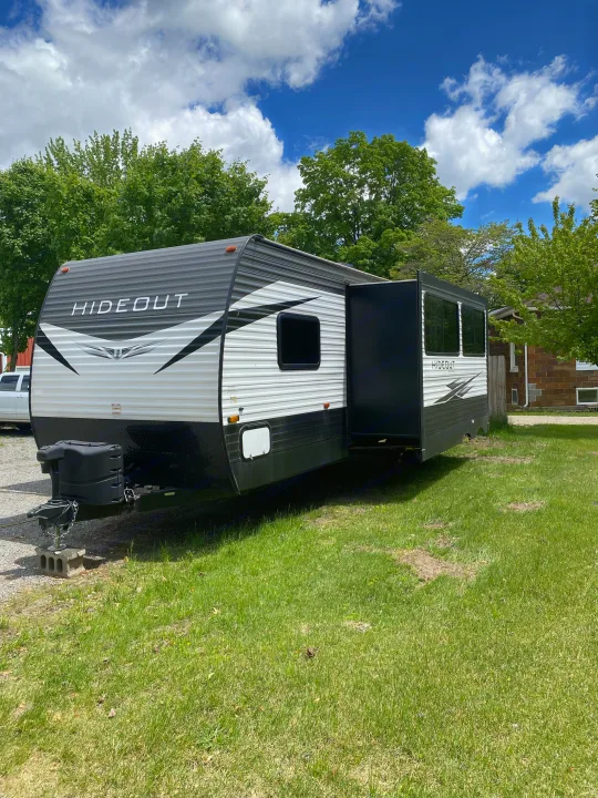 Spacious travel trailer for rv rental, ready for camping adventures under a blue sky.. Keystone RV Hideout 2021