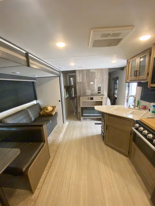 Spacious, modern RV rental interior with kitchen, dinette, and fireplace. Ideal for comfortable travel and camping.. Keystone RV Hideout 2021