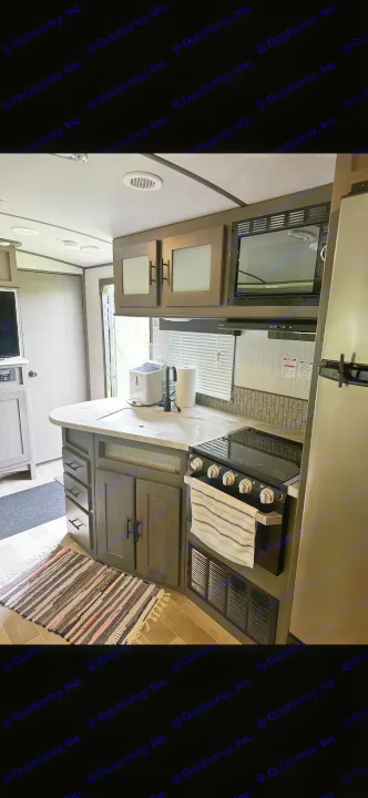 Step inside this modern RV rental's full kitchen, featuring a sink, stove, microwave, and fridge, ideal for comfortable travel.. Cruiser RV MPG Ultra Lite 2021