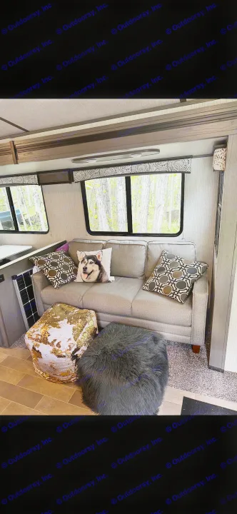 Cozy RV rental interior with gray couch, dog pillow, gold sequin & black furry ottomans. Windows show nature views.. Cruiser RV MPG Ultra Lite 2021