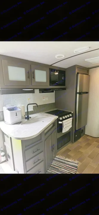 RV rental kitchen: modern dark cabinets, light countertop, sink, ice maker, microwave, fridge, and stove.. Cruiser RV MPG Ultra Lite 2021