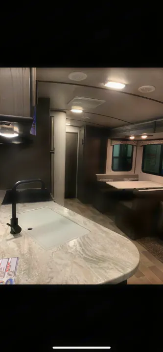 Spacious RV rental interior featuring a modern kitchen island with sink and a cozy dinette area for comfortable living.. Cruiser RV MPG Ultra Lite 2021