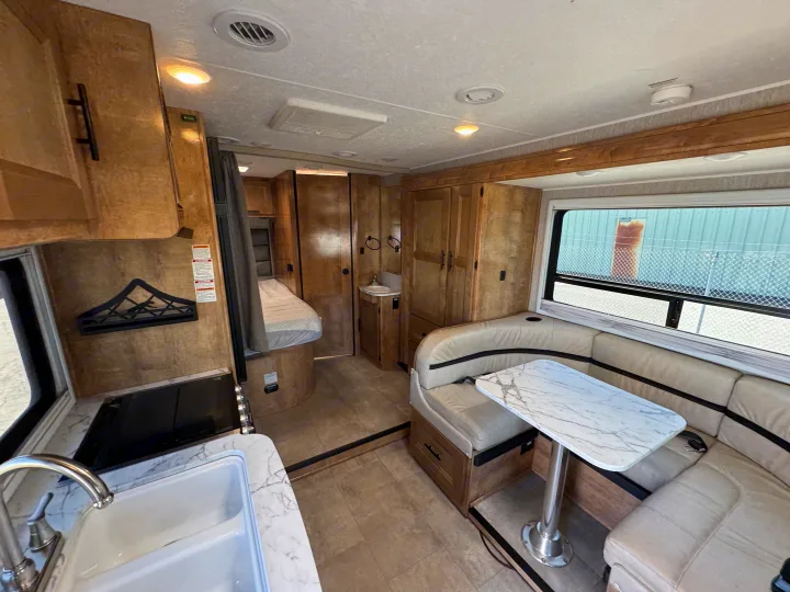 Explore this RV rental's inviting interior: compact kitchen, comfy dinette, bedroom, and bath.. Coachman Prism Select 24 CB 2021