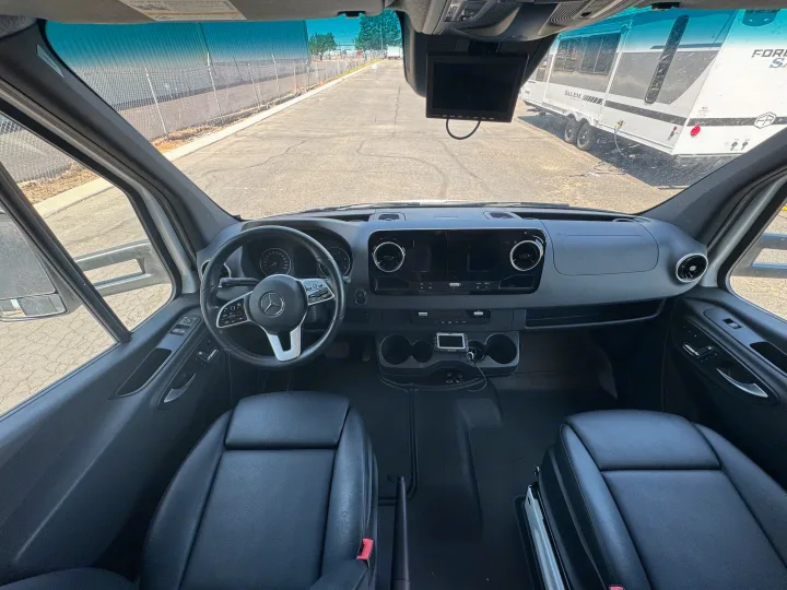 Spacious Mercedes van interior, perfect for an rv rental adventure. Shows dashboard & parked RV trailer outside.. Coachman Prism Select 24 CB 2021