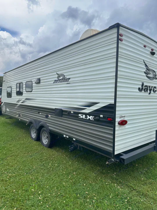 Spacious Jayco Jay Flight SLX travel trailer on green grass under cloudy skies, ready for your next RV rental adventure.. Jayco Jay Flight SLX 2022