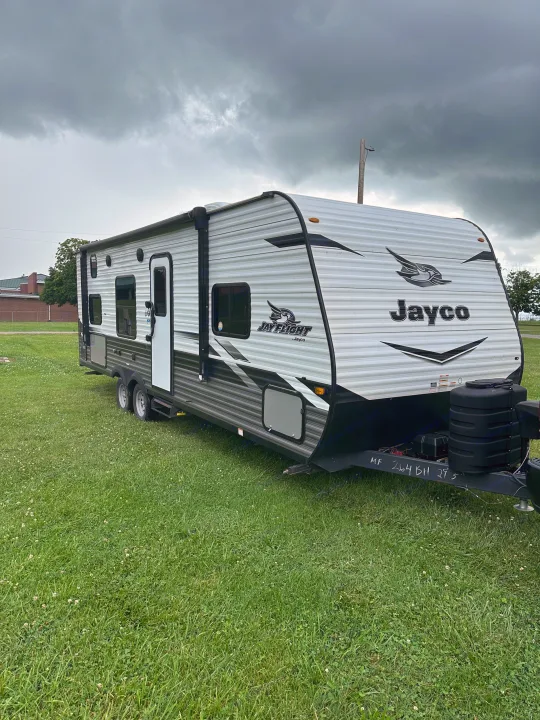 RV rental: Jayco Jay Flight travel trailer parked on grass under a cloudy sky, ready for your next adventure.. Jayco Jay Flight SLX 2022