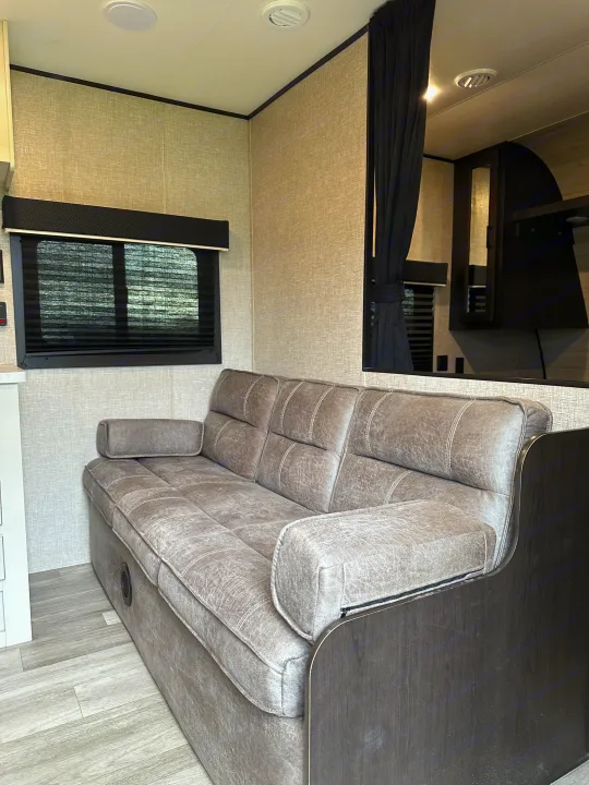 Spacious RV rental interior featuring a comfortable grey sofa, window blinds, and modern design elements.. Jayco Jay Flight SLX 2022