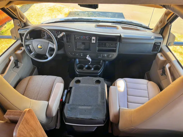 Overhead view of an RV rental cockpit, showing the dashboard, steering wheel, and front seats with a center console.. Jayco Redhawk SE 2019