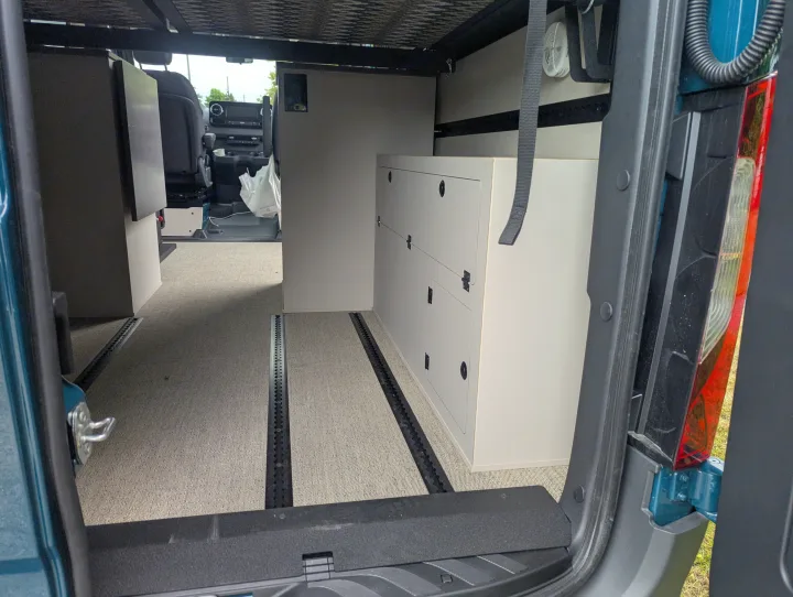 RV rental: Spacious camper van interior with modular cabinets, comfy carpet, and track flooring system.. Mercedes-Benz Sprinter 2025