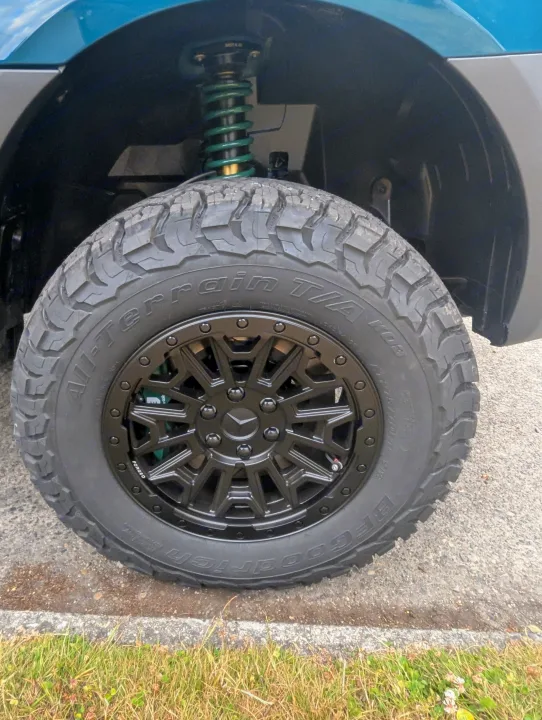 Close-up of a BFGoodrich All-Terrain tire and black forged wheel on an RV rental, showcasing an upgraded green coil suspension.. Mercedes-Benz Sprinter 2025