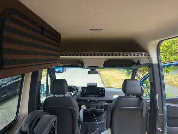 RV rental interior: View from the back into the spacious front cabin with dashboard, seats, and overhead storage.. Mercedes-Benz Sprinter 2025