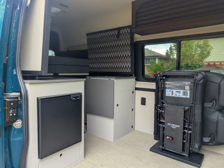 Explore this rv rental camper van interior: compact kitchenette with fridge, clever storage, and adaptable EZ Mount seating system.. Mercedes-Benz Sprinter 2025