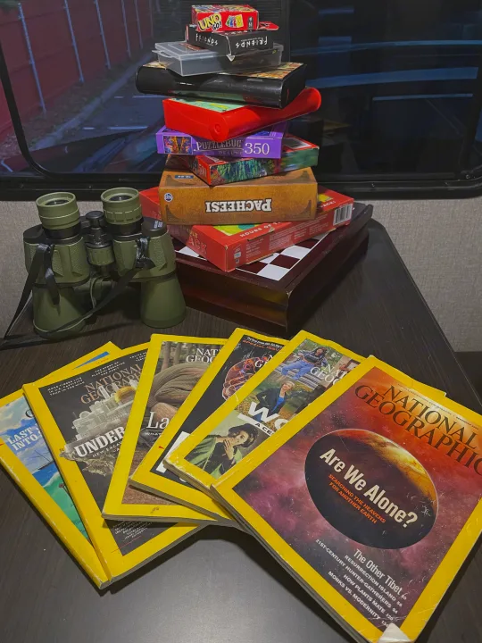 Inside an RV rental: a stack of games, puzzles, binoculars, & National Geographic magazines for travel entertainment.. Jayco Jay Flight SLX 2021