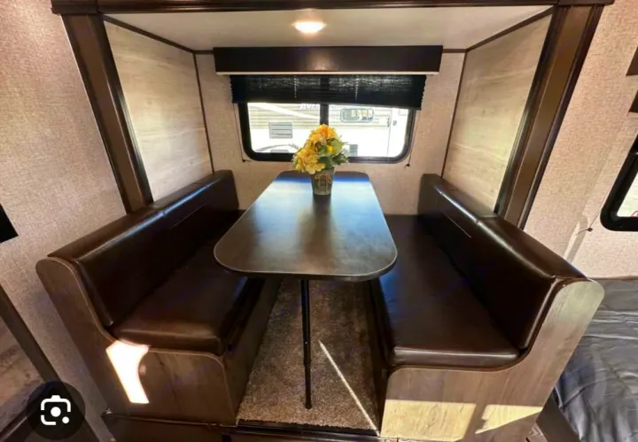 Cozy RV rental dinette with dark brown upholstered benches and a functional table. A window offers natural light and views.. Jayco Jay Flight SLX 2021