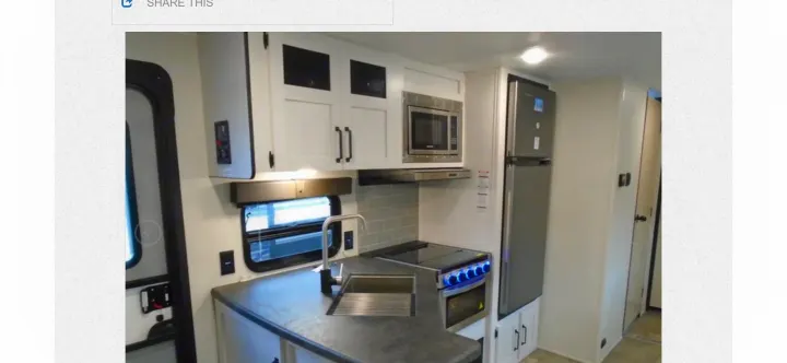 RV rental kitchen: modern white cabinets, stainless steel fridge, microwave, stove, sink, and grey tiled backsplash.. Palomino PUMA XLE 2023
