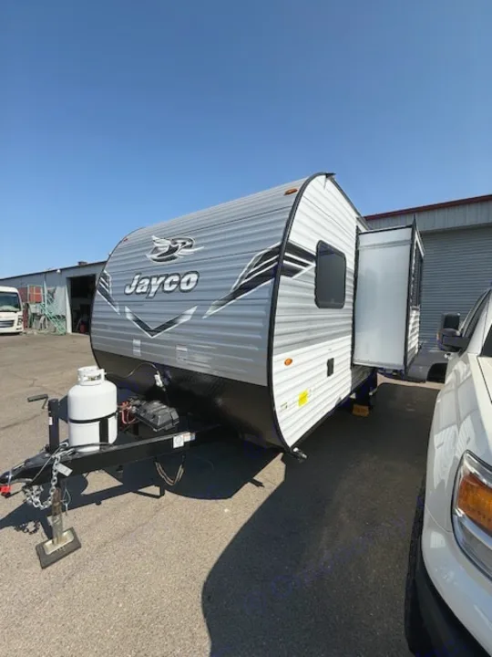 Bright blue sky over a parked grey Jayco travel trailer with a slide-out extended, perfect for your next RV rental.. JAYCO Jay Flight 2025