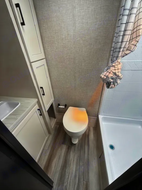 Inside this RV rental: a compact and clean bathroom featuring a toilet, sink, and shower with a plaid curtain.. JAYCO Jay Flight 2025