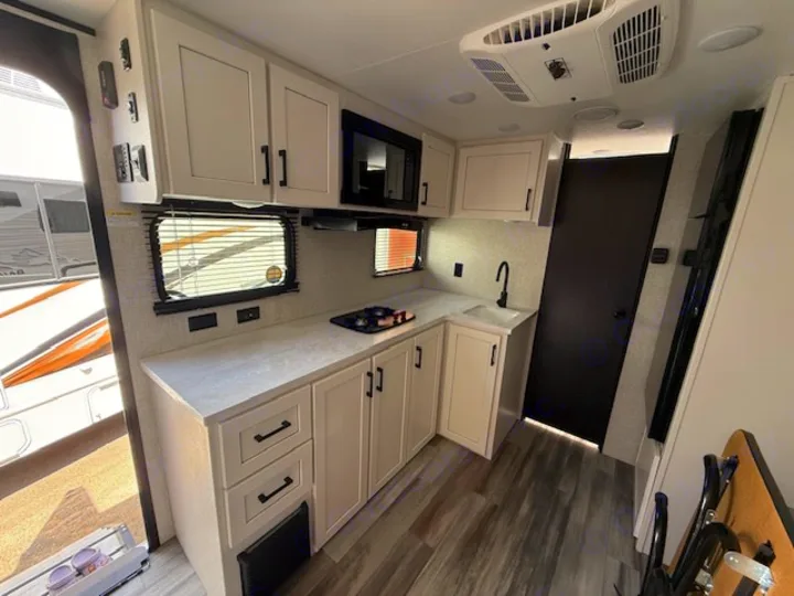 Bright rv rental kitchen interior featuring modern light cabinets, built-in appliances, sink, and wood-look floor.. JAYCO Jay Flight 2025
