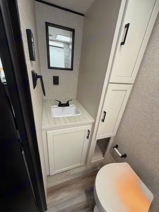 Modern RV rental bathroom features a vanity with sink, mirror, toilet, and ample storage cabinets.. JAYCO Jay Flight 2025