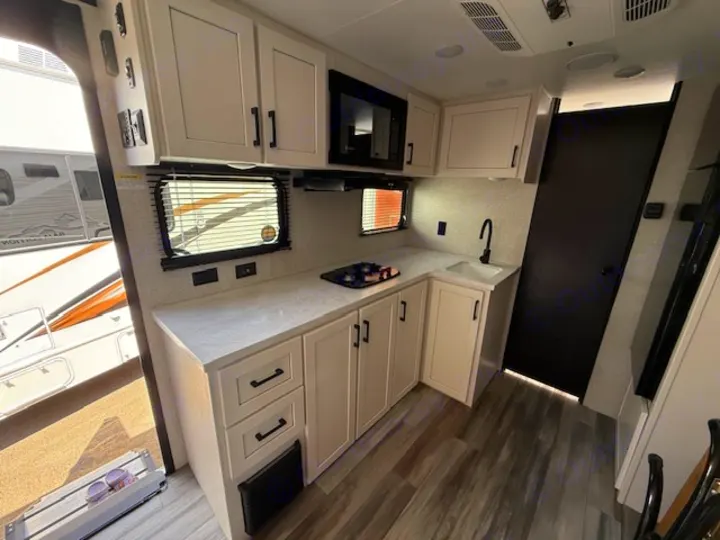 Spacious rv rental kitchen with light cabinets, appliances, sink, and wood-look floor, perfect for your next adventure.. JAYCO Jay Flight 2025