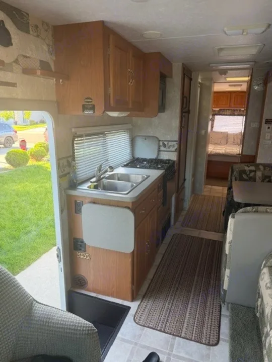 Spacious RV rental interior with a kitchenette, dining area, and rear bedroom.. Coachmen Mirada Deluxe/Premier 2004
