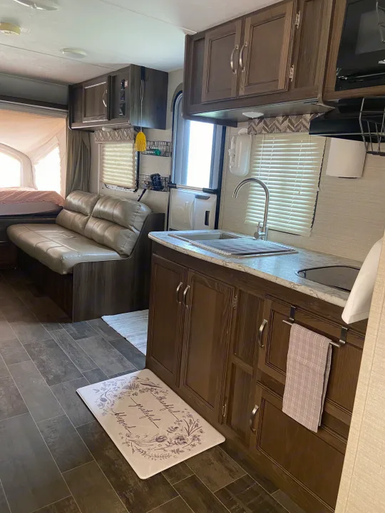 This RV rental's inviting interior features a modern kitchen, comfortable living area, and cozy pop-out bed.. Keystone RV Bullet Crossfire 2018