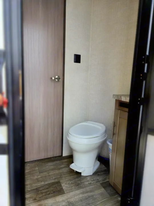 RV rental bathroom with white toilet, wood-look floor, vanity, and textured walls.. Crossroads RV Sunset Trail Super Lite 2021