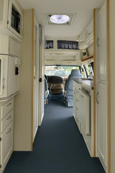 Inside an rv rental: blue carpeted aisle leads to the cockpit. White cabinets, kitchenette, and microwave visible.. Pleasure Way Excel 2001