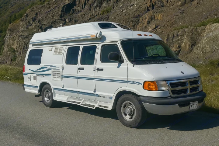 A white camper van, an ideal RV rental, is parked on a paved road with rocky cliffs and green vegetation in the background.. Pleasure Way Excel 2001