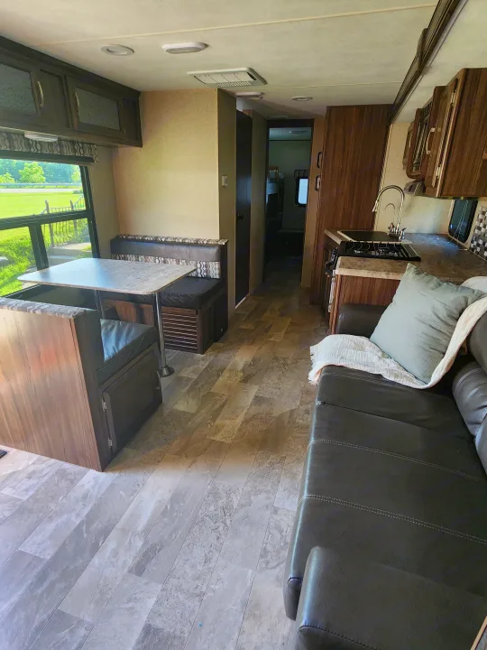 Inside this RV rental: a spacious living area with a sofa, dinette, and full kitchen, perfect for travel.. Coachmen Apex 2018