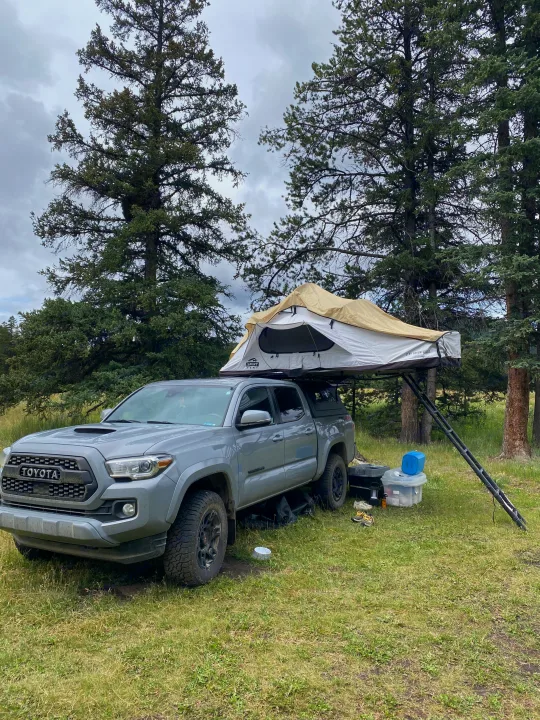 Grey Toyota Tacoma with a rooftop tent deployed for truck camping. A great alternative to rv rental for outdoor adventures.. Toyota Tacoma 2020