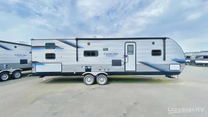 Explore this spacious grey and blue Catalina travel trailer, perfect for your next RV rental. Parked under cloudy skies.. Coachmen Catalina Legacy Edition 2022