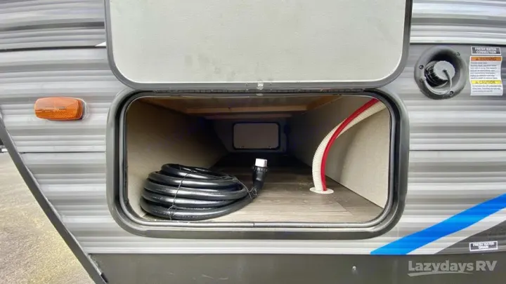 Exterior view of an RV rental's pass-through storage, equipped with power cord and water hose for convenient travel.. Coachmen Catalina Legacy Edition 2022