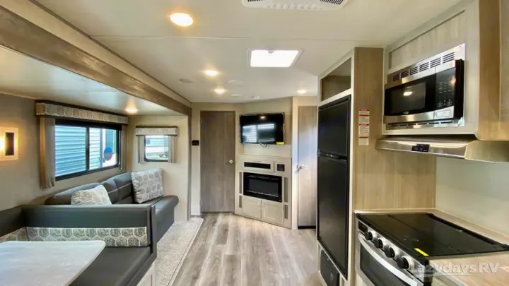 Modern RV rental interior showcasing a living area with sofa, dinette, kitchen, and electric fireplace.. Coachmen Catalina Legacy Edition 2022
