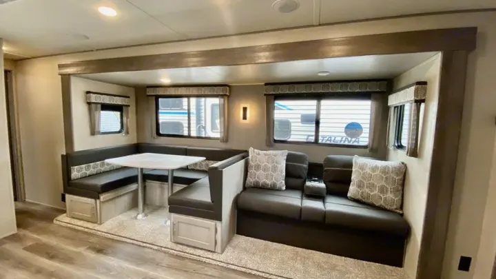 This RV rental offers a versatile U-shaped dinette for meals and a cozy lounge area with windows, ideal for relaxing travel.. Coachmen Catalina Legacy Edition 2022