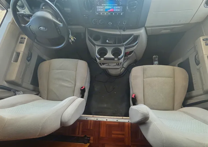 Ford RV rental interior: Driver's cockpit of an E-Series van with steering wheel, multimedia screen, and light fabric seats.. Jamboree Sport 2011