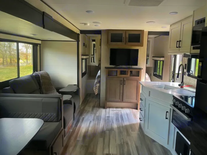 Modern RV rental interior: kitchen with sink & stove, living area with couch, dinette, and entertainment center. Bright & inviting.. Jayco Jay Flight SLX 2024