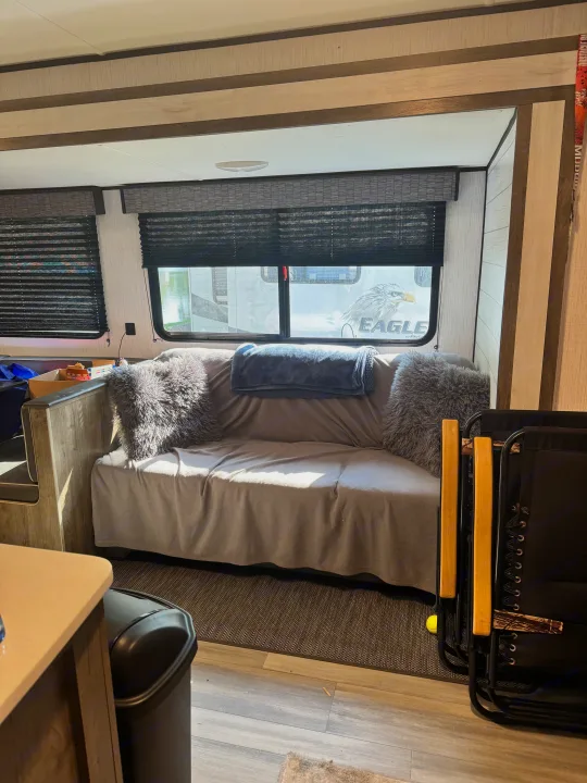 Inside an RV rental: a comfy living space with a sofa, plush pillows, and windows, ideal for relaxing during your travels.. Heartland RVs Pioneer 2022