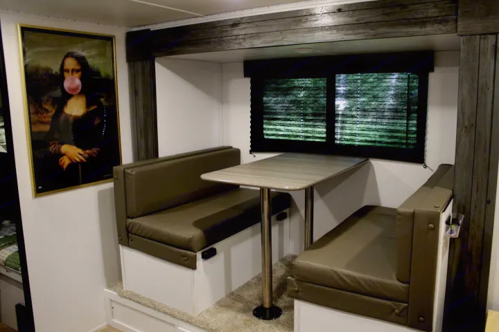 Cozy rv rental dinette featuring plush benches, a light table, and a humorous Mona Lisa art piece.. Keystone RV Hideout 2022